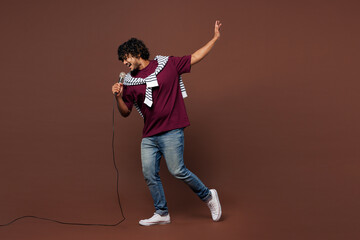 Full body side view young Indian man he wear purple t-shirt sweatshirt tied over shoulders casual...