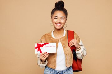 Young smart girl student wear casual clothes backpack bag hold gift certificate coupon voucher card for store isolated on plain pastel light beige background. High school university college concept.