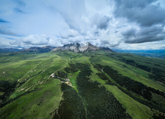 Naklejka premium Aerial view of beautiful high altitude snow capped mountains and forest grassland landscape in China