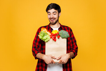 Young shocked surprised man he wear casual clothes hold look at craft paper bag for takeaway mock...