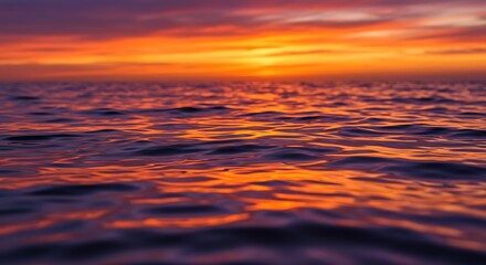 Fototapeta premium Vibrant sunset colors reflected on a calm ocean surface.