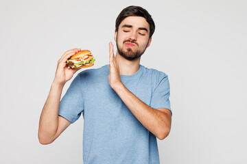 Young man he wear blue t-shirt casual clothes hold eat burger do stop palm gesture say no to...