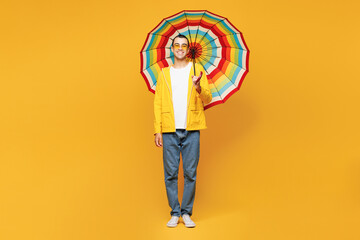Full body young fun middle eastern man he wears waterproof raincoat outerwear casual clothes hold...