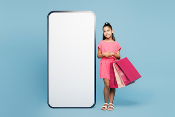 Little kid girl 9-10 years old wear pink clothes hold package bags after shopping look at big huge...