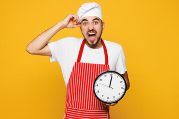 Young shocked sad housewife housekeeper chef cook baker man wears red apron toque hat hold in hand...