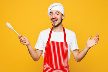 Young shocked surprised happy housewife housekeeper chef cook man wears red apron toque hat hold in...