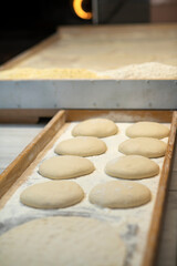 Scene from a traditional bakery baking Turkish flat bread called pide with unbaked bread waiting to be placed to the oven