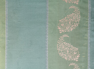 Top view close up detail of green cotton fabric with cream colored threadwork embroidery