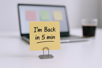 Naklejka premium Office Break Reminder: Note Saying 'Back in 5 Minutes' on Desk with Laptop