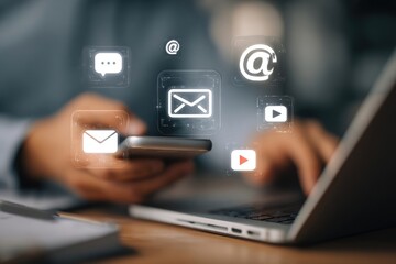 Close-up of hands using laptop and phone, email and communication icons overlayed