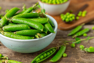 Fresh green pea pods with green peas on a wooden background. Sweet green peas. Green pea beans vegetables. Vegan. healthy vegetable. Copy space