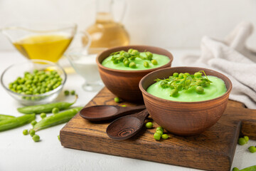 Green pea soup on a wooden table. Fresh pea soup bowl. Delicious healthy cream soup in a bowl with green peas and croutons. Healthy vegan puree. Copy space. Space for text.