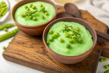 Green pea soup on a wooden table. Fresh pea soup bowl. Delicious healthy cream soup in a bowl with green peas and croutons. Healthy vegan puree. Copy space. Space for text.