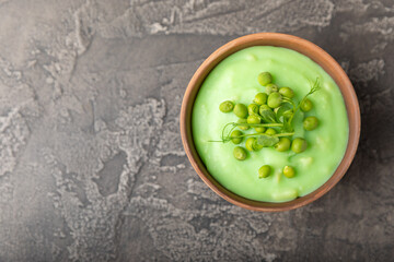 Green pea soup on a wooden table. Fresh pea soup bowl. Delicious healthy cream soup in a bowl with green peas and croutons. Healthy vegan puree. Copy space. Space for text.