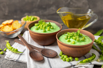 Green pea soup on a wooden table. Fresh pea soup bowl. Delicious healthy cream soup in a bowl with green peas and croutons. Healthy vegan puree. Copy space. Space for text.