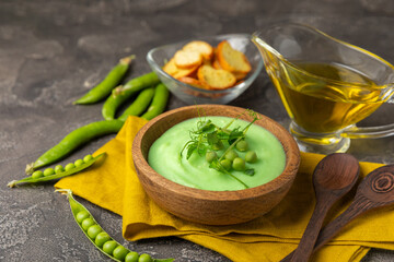 Green pea soup on a wooden table. Fresh pea soup bowl. Delicious healthy cream soup in a bowl with green peas and croutons. Healthy vegan puree. Copy space. Space for text.