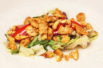 Making tortilla wrap with fresh ingredients. Chicken pieces, lettuce, and red bell pepper on flatbread. Preparing homemade lunch or dinner. Wrapping tasty filling inside soft wheat tortilla.