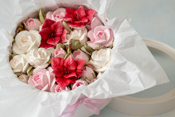 Beautiful arrangement of artificial flowers in a round box, featuring vibrant red and soft pink blooms, elegantly wrapped in tissue paper, perfect for gifting or decoration