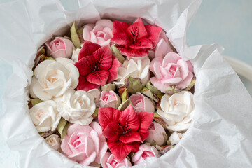 Beautiful arrangement of pink and red artificial flowers in a round box, surrounded by delicate white tissue paper, creating an elegant and vibrant floral display for decoration