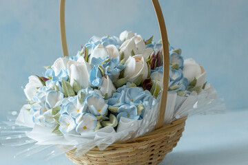 Beautiful floral arrangement in a woven basket featuring delicate blue and white flowers,...