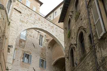 Archway connecting two historical buildings in Perugia, Italy, featuring ancient stone walls and...
