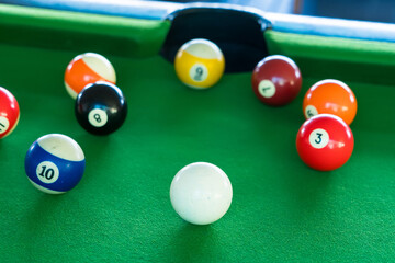 A close-up view of a colorful set of billiard balls on a green pool table, ready for a billiards...
