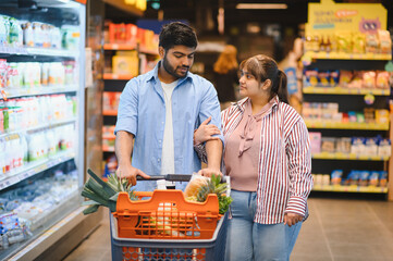 Indian couple choosing groceries in supermarket