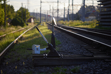 Railway switch lever constructed from metal and wood positioned on gravel track. Manual operation mechanism allows redirection of train routes. Essential for railway infrastructure and logistic manage