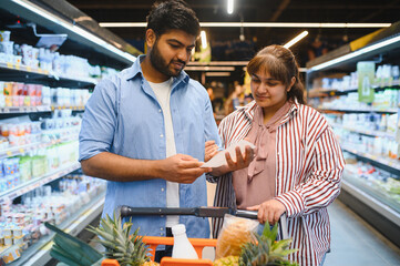 Indian couple checking shopping list in grocery store