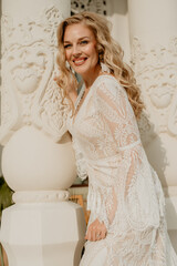 Beautiful slim blonde poses in boho wedding dresses and an embroidered corset on a summer terrace.