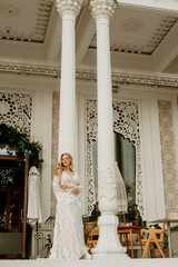  Beautiful slim blonde poses in boho wedding dresses and an embroidered corset on a summer terrace.
