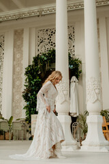  Beautiful slim blonde poses in boho wedding dresses and an embroidered corset on a summer terrace.