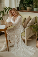  Beautiful slim blonde poses in boho wedding dresses and an embroidered corset on a summer terrace.