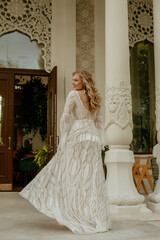  Beautiful slim blonde poses in boho wedding dresses and an embroidered corset on a summer terrace.