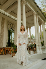  Beautiful slim blonde poses in boho wedding dresses and an embroidered corset on a summer terrace.