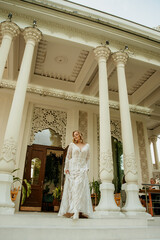  Beautiful slim blonde poses in boho wedding dresses and an embroidered corset on a summer terrace.