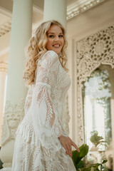  Beautiful slim blonde poses in boho wedding dresses and an embroidered corset on a summer terrace.