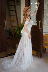  Beautiful slim blonde poses in boho wedding dresses and an embroidered corset on a summer terrace.