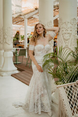  Beautiful slim blonde poses in boho wedding dresses and an embroidered corset on a summer terrace.