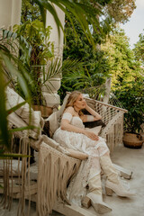  Beautiful slim blonde poses in boho wedding dresses and an embroidered corset on a summer terrace.