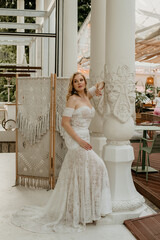  Beautiful slim blonde poses in boho wedding dresses and an embroidered corset on a summer terrace.