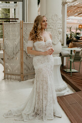  Beautiful slim blonde poses in boho wedding dresses and an embroidered corset on a summer terrace.