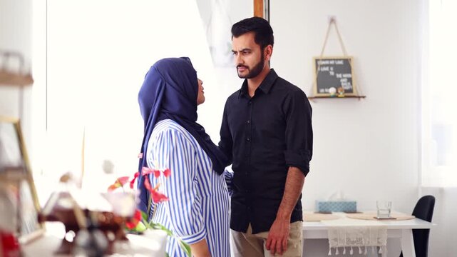 A loving Muslim couple standing in the living room of their home

