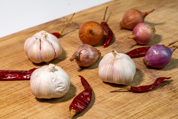 Combination of garlic bulbs, dried red chili peppers, and shallot onions isolated on a clean white background for cooking and seasoning concept