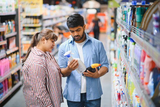 Indian couple choosing cleaning products in supermarket household chemicals aisle