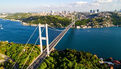 Aerial view of a long suspension bridge spanning a body of water, with a city skyline in the background (1)