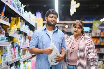 Indian couple choosing detergent in household chemicals store