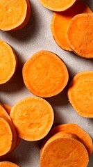 A close up of several slices of sweet potatoes spread out on a light gray surface in a vertical shot