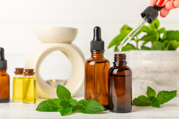 Essential oil mint on a wooden background. Peppermint essential oil with fresh mint leaves. A bottle of aromatherapy oil. Mint extract. The concept of natural cosmetics, spa care. copy space
