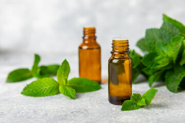 Essential oil mint on a wooden background. Peppermint essential oil with fresh mint leaves. A bottle of aromatherapy oil. Mint extract. The concept of natural cosmetics, spa care. copy space